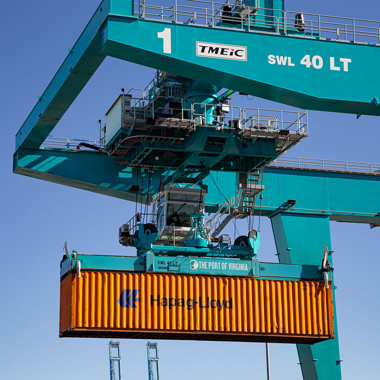 Close-up of an automated crane lifting a container in the air