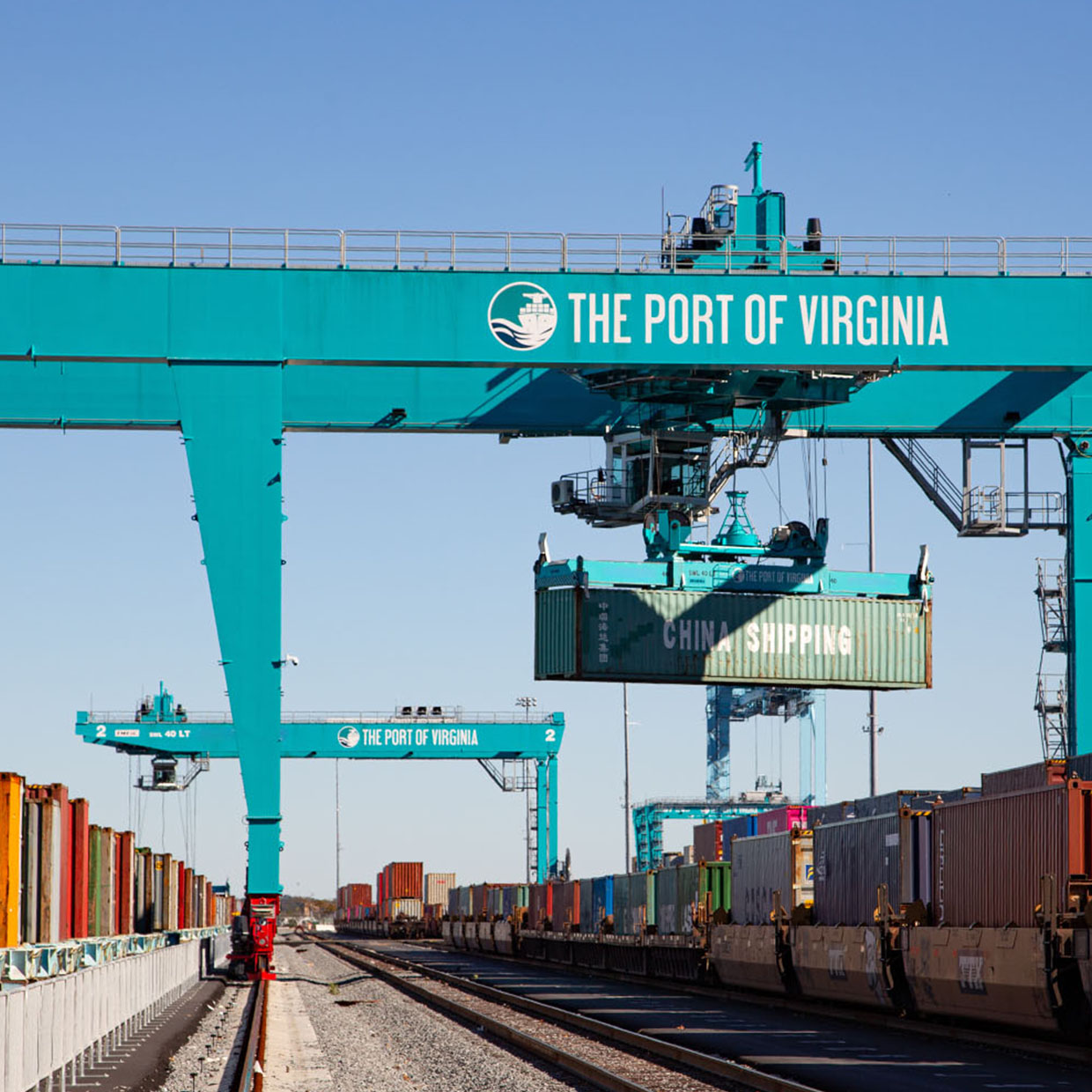 Multiple cranes lift cargo containers over train cars