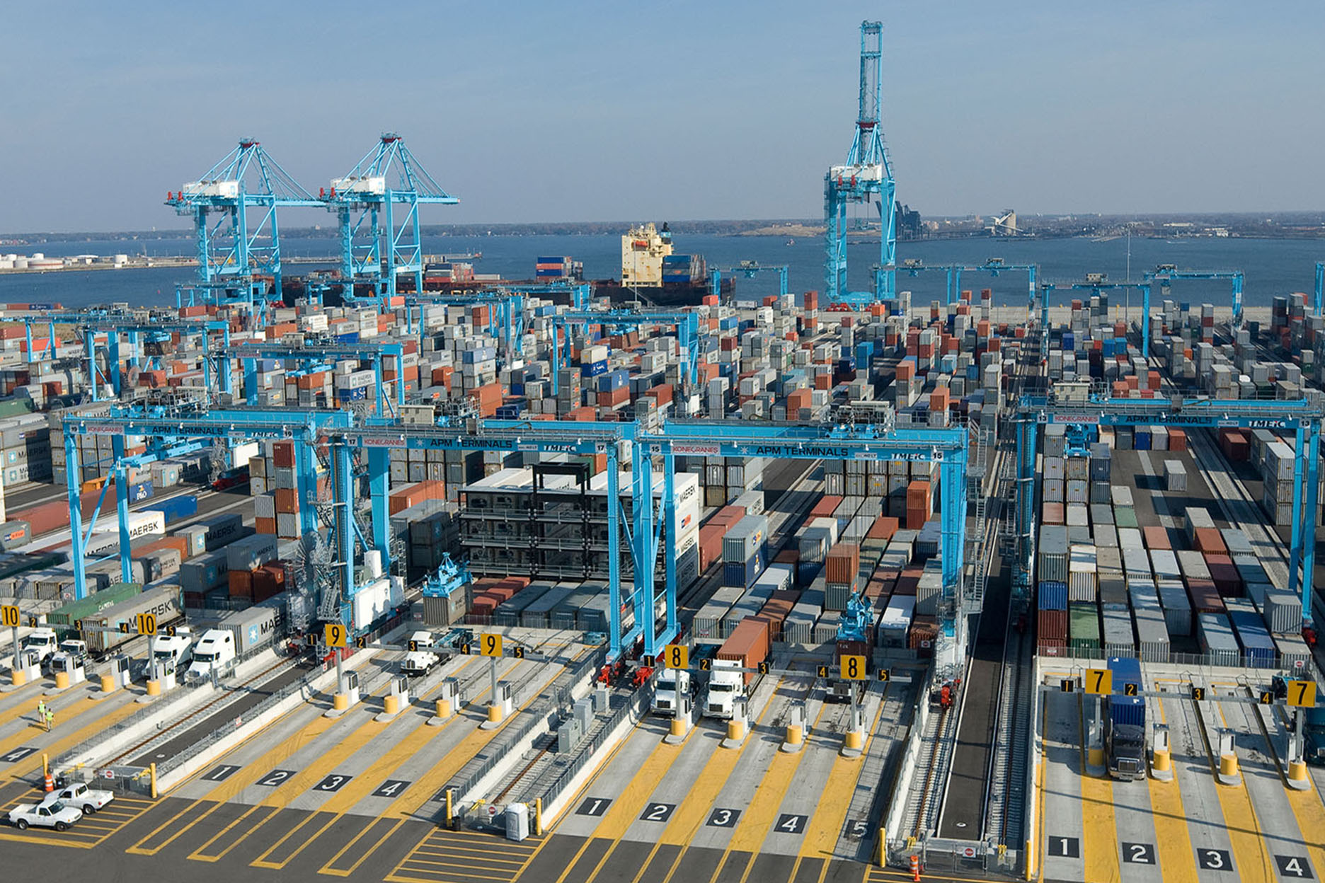 A busy shipping port with various container stacks and large cranes loading and unloading cargo