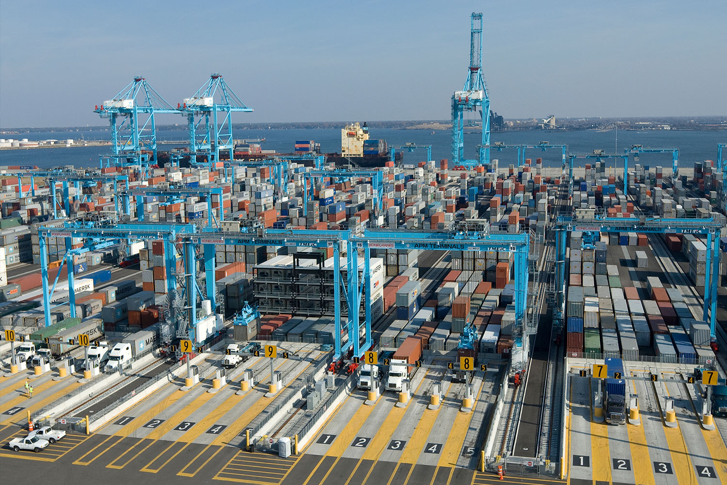 A busy shipping port with various container stacks and large cranes loading and unloading cargo