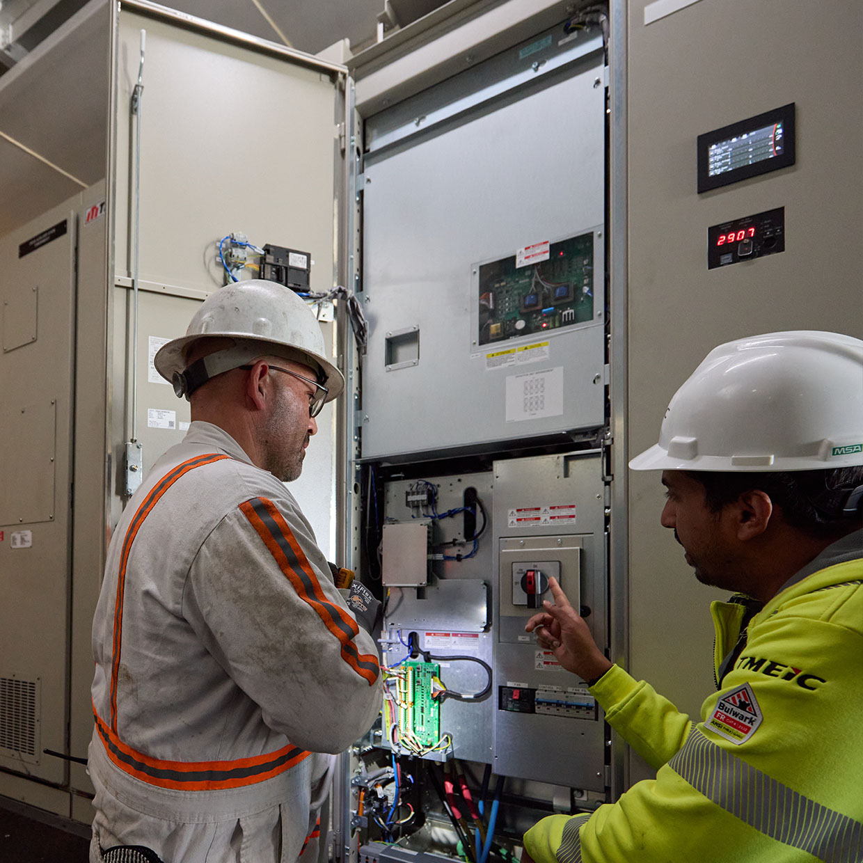 Two workers inspecting an electrical control panel