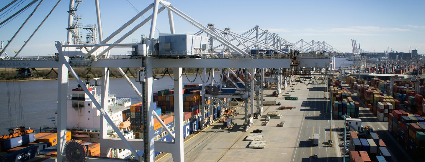A busy port terminal with multiple cranes lifting and transporting cargo containers